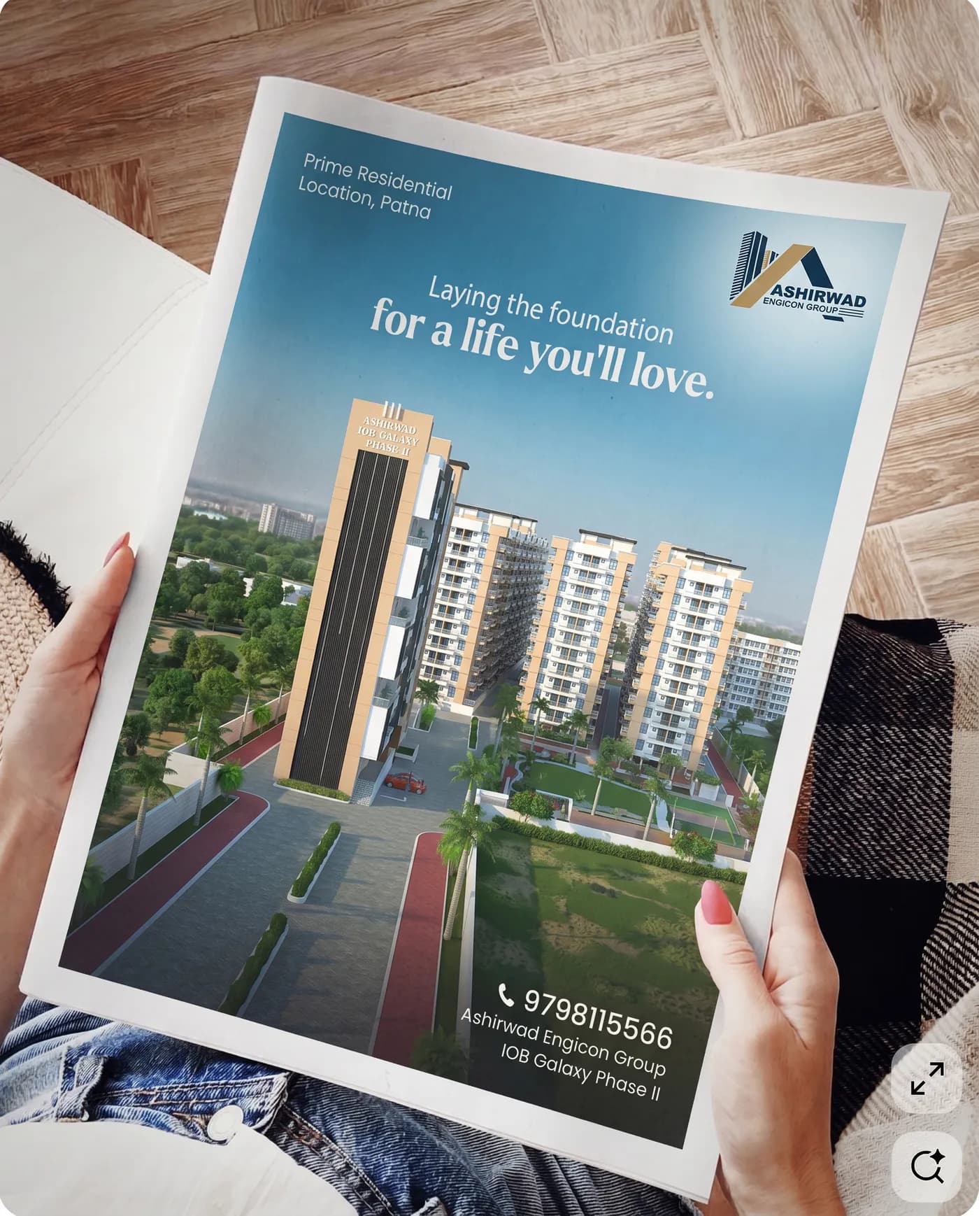 The full-page press ad held open, reading Laying the foundation for a life you'll love, above a render of the completed towers and the booking number.