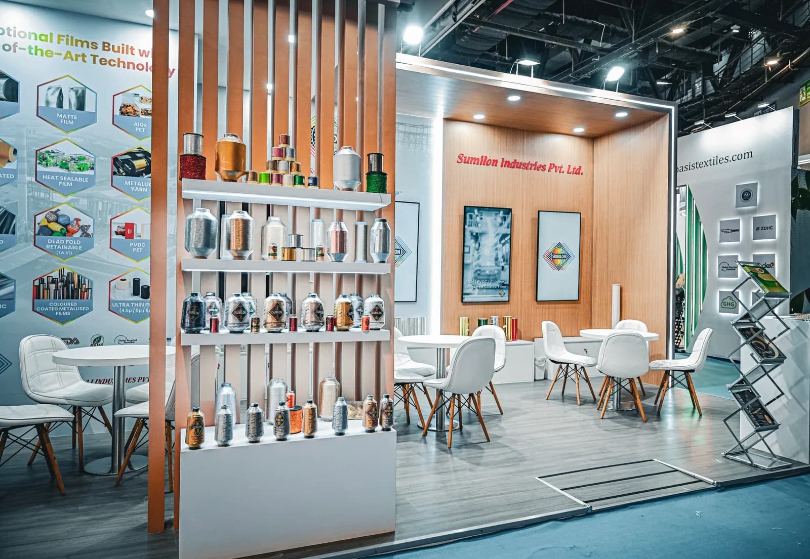 A detail of a stand: a slatted timber screen with product shelved into it, beside an information wall and a small meeting setting.