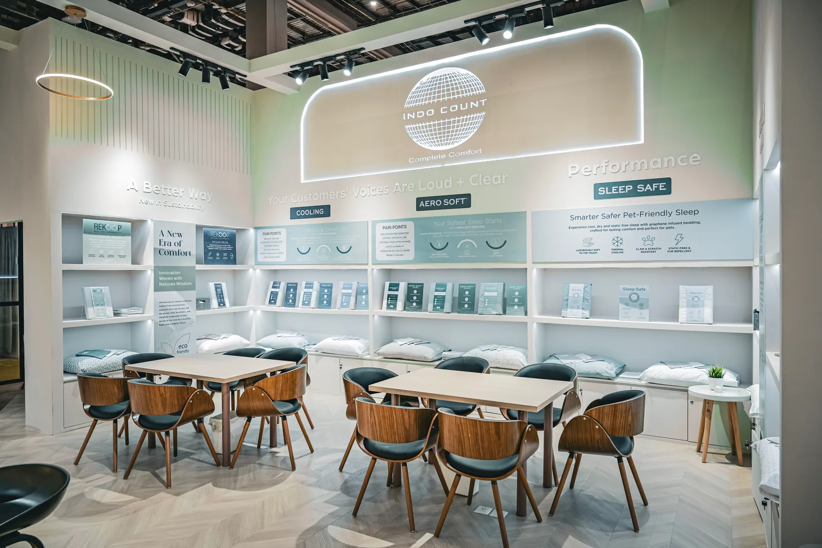 The Sleep Safe stand in mint and white: curved signage over a wall of product panels, with tables and rattan chairs set out in front.