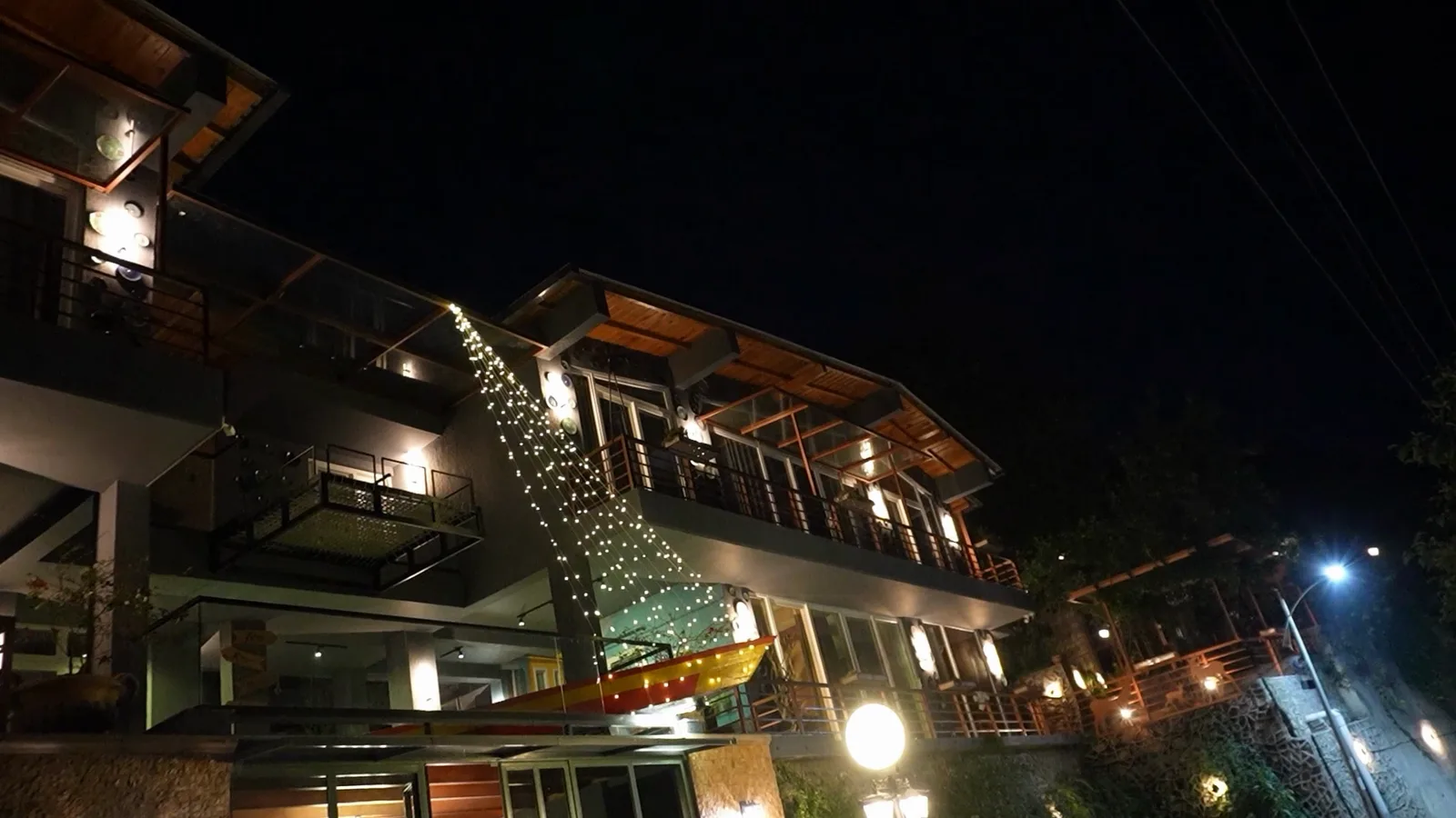 The property after dark: three storeys of terraces lit warm against the hillside.